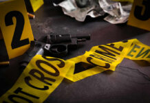 Gun surrounded by crime scene tape and evidence markers