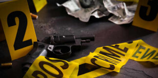 Gun surrounded by crime scene tape and evidence markers