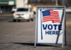 Vote Here sign with American flag.