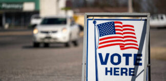 Vote Here sign with American flag.