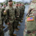Iran’s Bleed-Out Plan Targets U.S. Forces Military personnel standing in formation outdoors