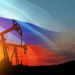 Oil pumps silhouetted against Russian flag and sunset.
