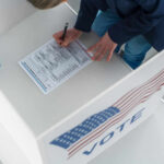 Person filling out a ballot at voting booth.