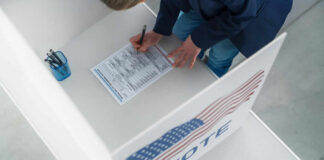 Person filling out a ballot at voting booth.
