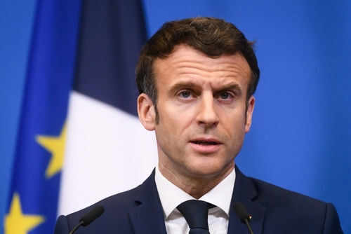 Man speaking at press conference with flags behind