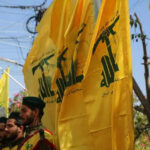 Beirut Sky ERUPTS Over Hezbollah Stronghold Men in military attire with yellow flags outdoors