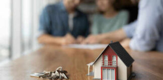 Model house and keys on a wooden table