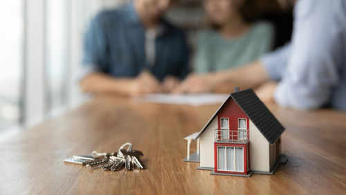 Model house and keys on a wooden table