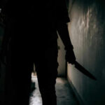Mother’s Terror: Surviving a Son’s Knife Assault Silhouette of person holding knife in dark corridor