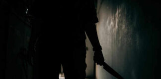 Silhouette of person holding knife in dark corridor