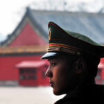 A military guard in uniform standing in profile against a historical building