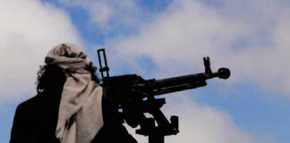 Silhouette of an armed individual with a mounted weapon against a cloudy sky