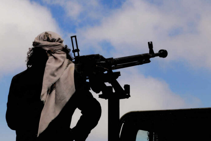 Silhouette of an armed individual with a mounted weapon against a cloudy sky