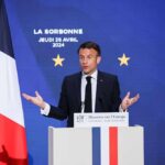 Macron’s Bold Move: Hormuz Defense Plan Unveiled Emmanuel Macron delivering a speech at La Sorbonne with flags in the background