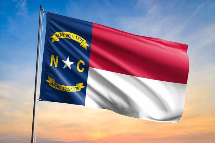 shutterstock_2468281617.jpg North Carolina state flag waving against a sunset sky