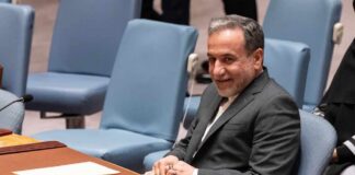 A man in a suit sitting at a conference table during a UN meeting