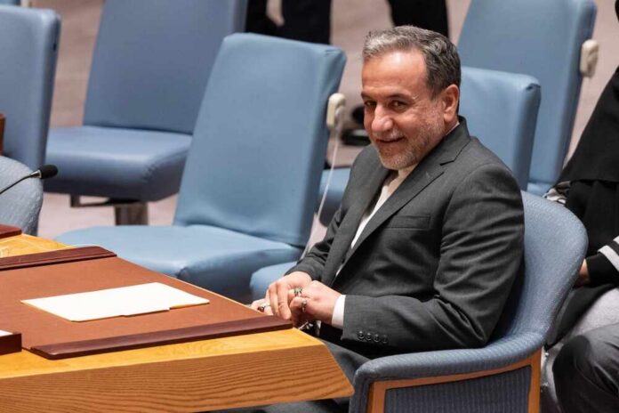 A man in a suit sitting at a conference table during a UN meeting