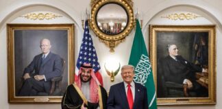 Two political leaders posing for a photo with flags in the background