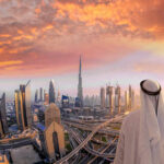 American Tourists Caught in Dubai’s Missile Frenzy A person in traditional attire overlooking the Dubai skyline at sunset