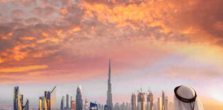 A person in traditional attire overlooking the Dubai skyline at sunset