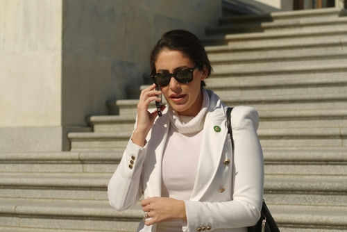 Person in white jacket talking on phone, wearing sunglasses.