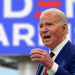 Biden’s Withdrawal Disaster: Explosive Report Looms Man in suit speaking in front of blue background.