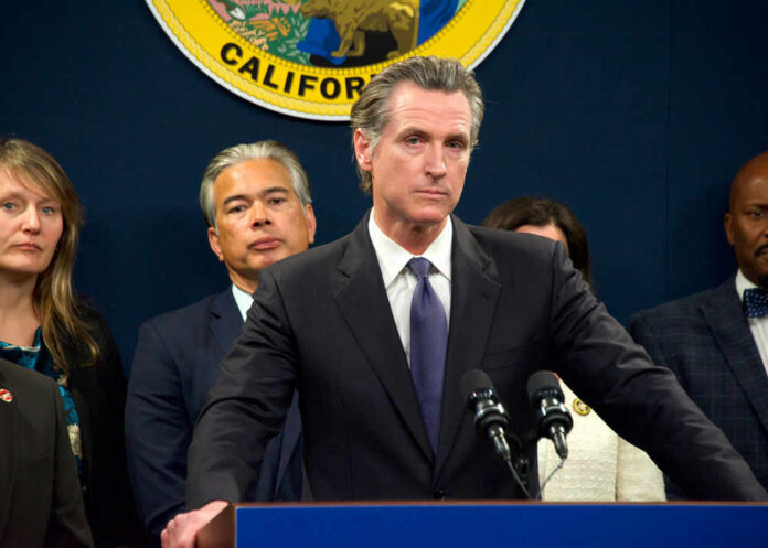 gavin-newsom638551334 Person speaks at podium with California seal behind.