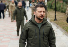SHAKEDOWN: Ukraine’s Battle Expertise Goes Global Zelensky walking outdoors with military personnel nearby.