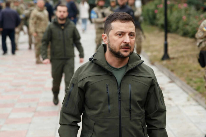 Zelensky walking outdoors with military personnel nearby.