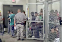 A group of individuals in a detention area with a law enforcement officer