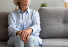 Elderly woman sitting on a couch with a thoughtful expression