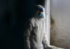 Healthcare worker in protective gear looking out of a window