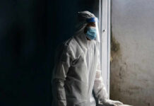 Healthcare worker in protective gear looking out of a window
