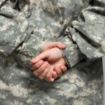 Classified War Plan Fuels Crypto Jackpot Person in military uniform with hands clasped behind their back