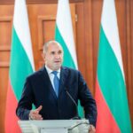 Pro-Russian Candidate CRUSHES Bulgaria Vote—NATO Rattled A politician delivering a speech at a podium with national flags in the background