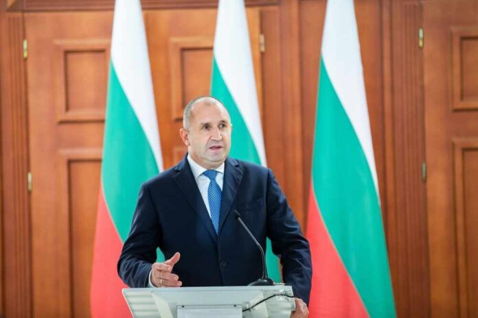 A politician delivering a speech at a podium with national flags in the background