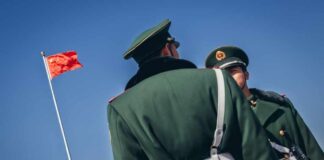 Two Chinese soldiers in uniform standing near the national flag