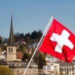 Swiss Seek EU Allies After U.S. Money Grab Swiss flag waving in front of historic buildings and church towers