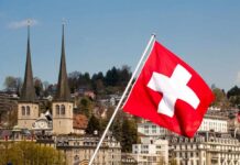 Swiss flag waving in front of historic buildings and church towers