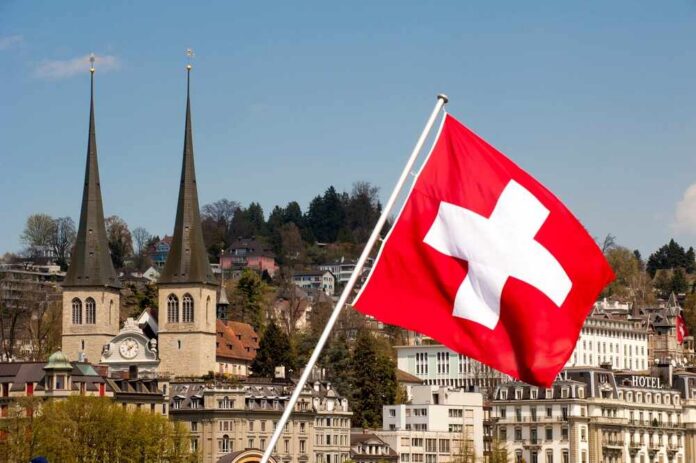 Swiss flag waving in front of historic buildings and church towers