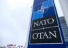 NATO sign with flags in the background