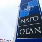 Shockwaves as Trump Floats NATO Exit NATO sign with flags in the background