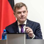 Germany Urges Restraint: Lebanon’s Humanitarian Toll Soars A man in a suit speaking at a podium with a microphone