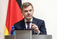 Germany Urges Restraint: Lebanon’s Humanitarian Toll Soars A man in a suit speaking at a podium with a microphone