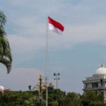 Indonesia’s Bold Betrayal Of Middle East Suppliers Indonesian flag waving in front of a building and palm trees