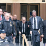 Health Drama Strikes Weinstein Retrial Man using walker surrounded by people in suits.