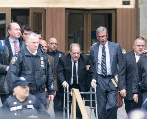 Man using walker surrounded by people in suits.