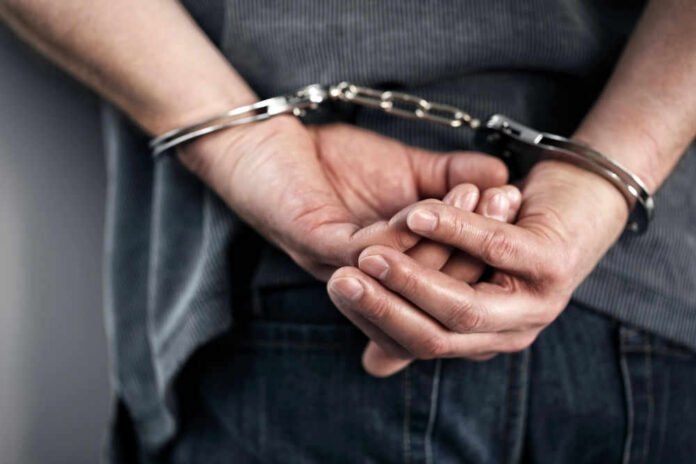 Person handcuffed with hands behind back.