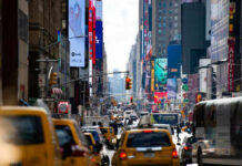 Manhattan’s Housing Crisis – Middle-Class DOOMED! Busy city street with taxis and billboards daytime