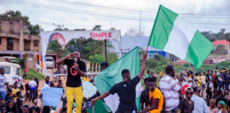 Crowd at a rally waving a large Nigerian flag